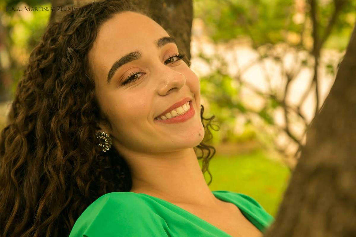 debutante sorrindo encostada na arvore