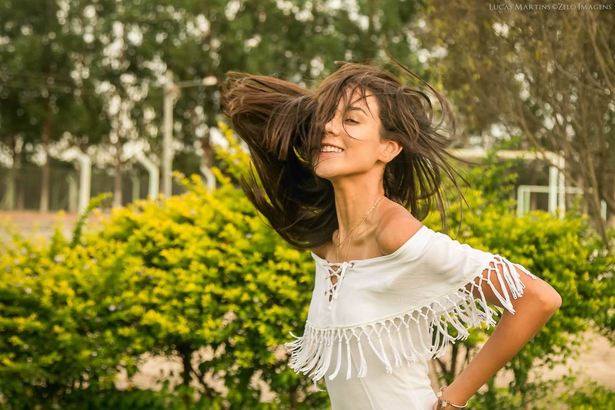 fotografia de debutante com cabelos ao vento e sorrindo durante ensaio fotográfico de 15 anos em Virgem da Lapa - MG