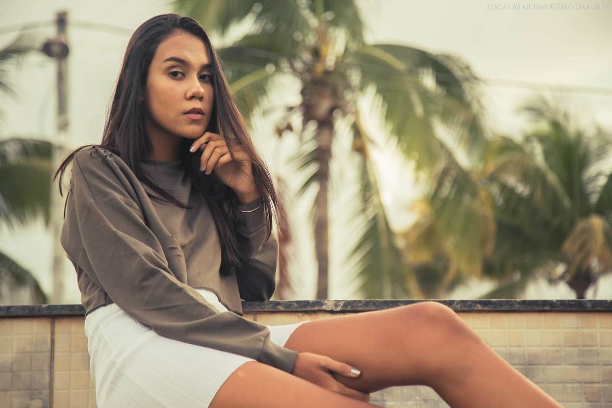 Fotografia da debutante posando sentada em uma escada, com mão no queixo, durante ensaio fotográfico de 15 anos em Virgem da Lapa - MG