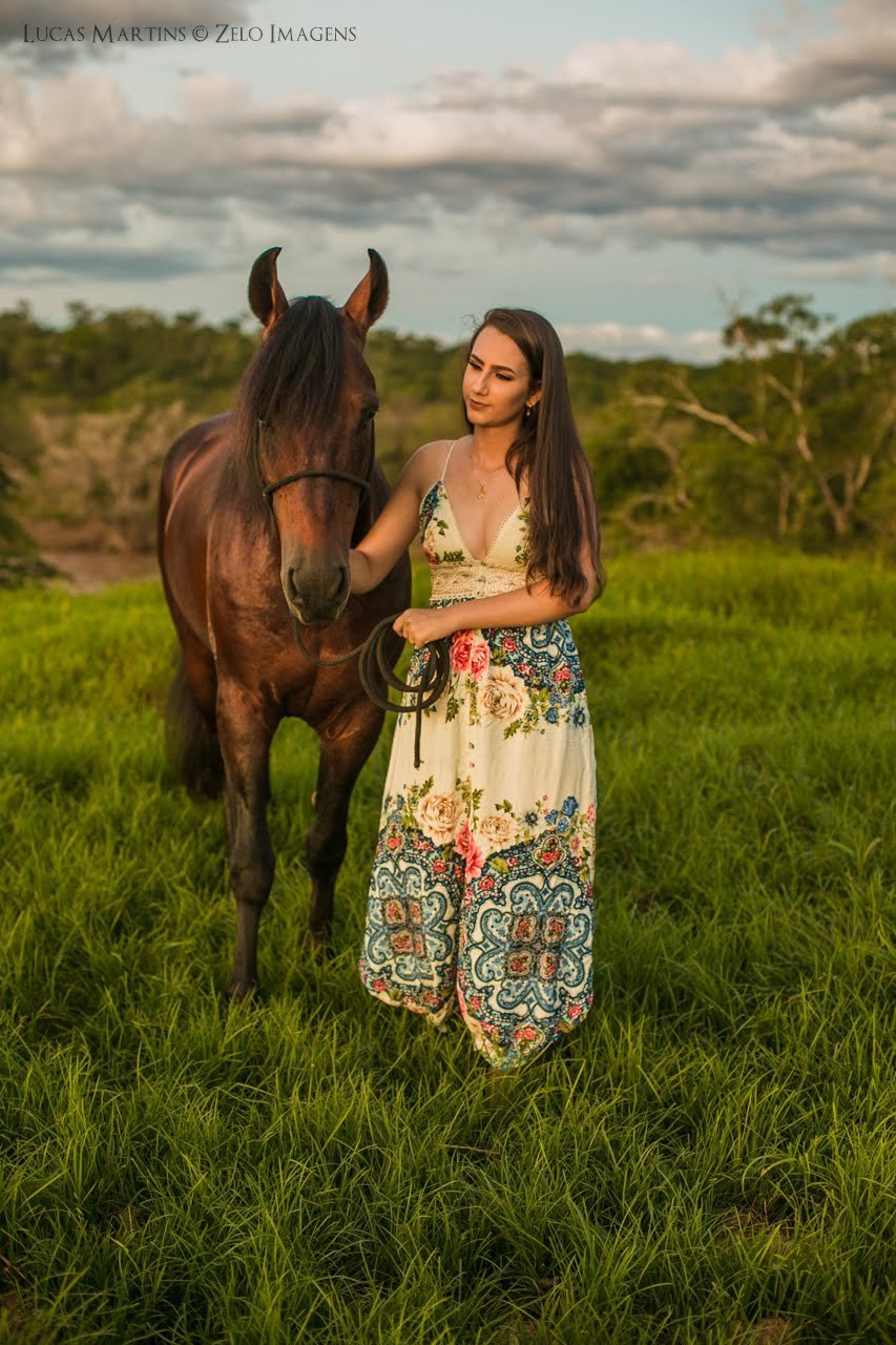 fotografia da debutante fazendo carinho em cavalo durante ensaio fotográfico 15 anos na cidade de Araçuaí, Minas Gerais
