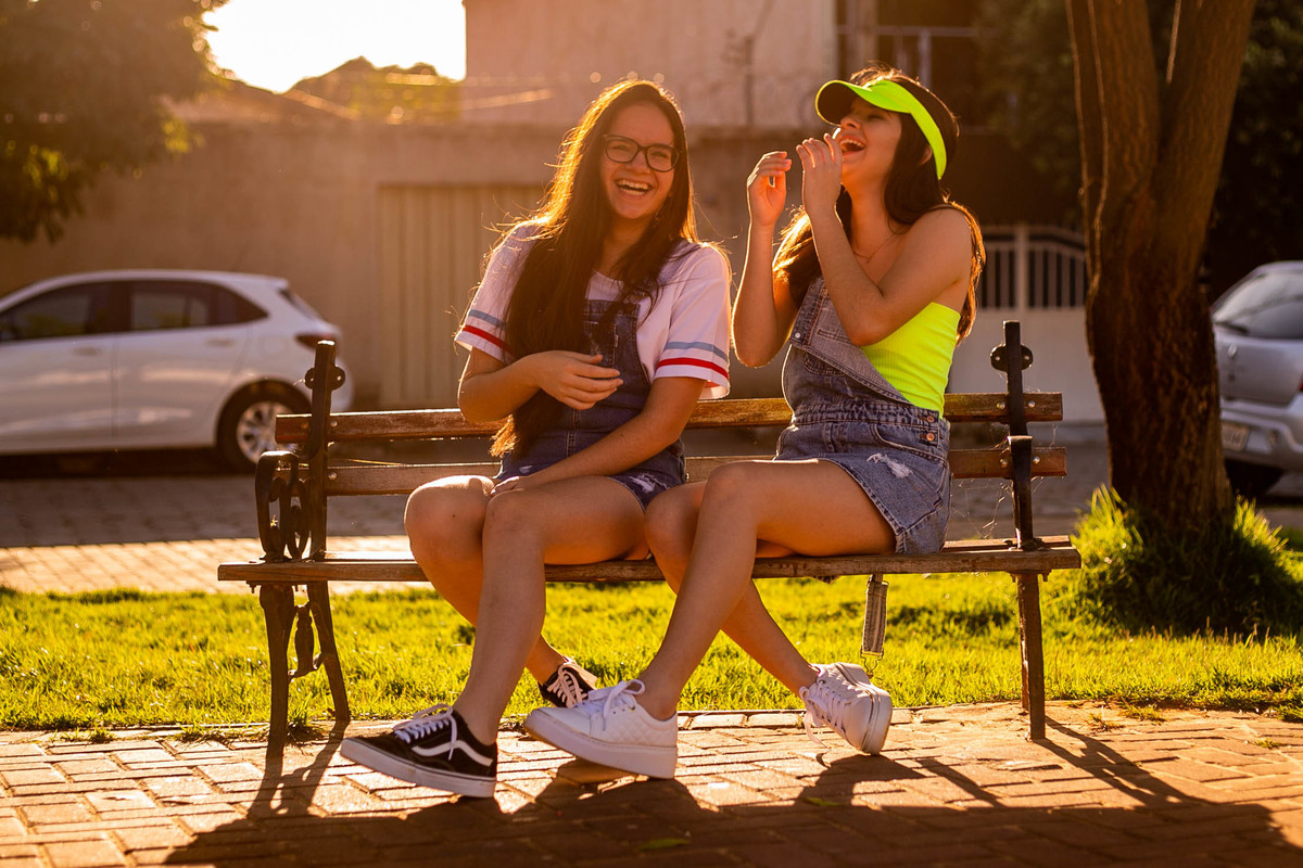 ensaio debutante junto com amiga sentada banco praca