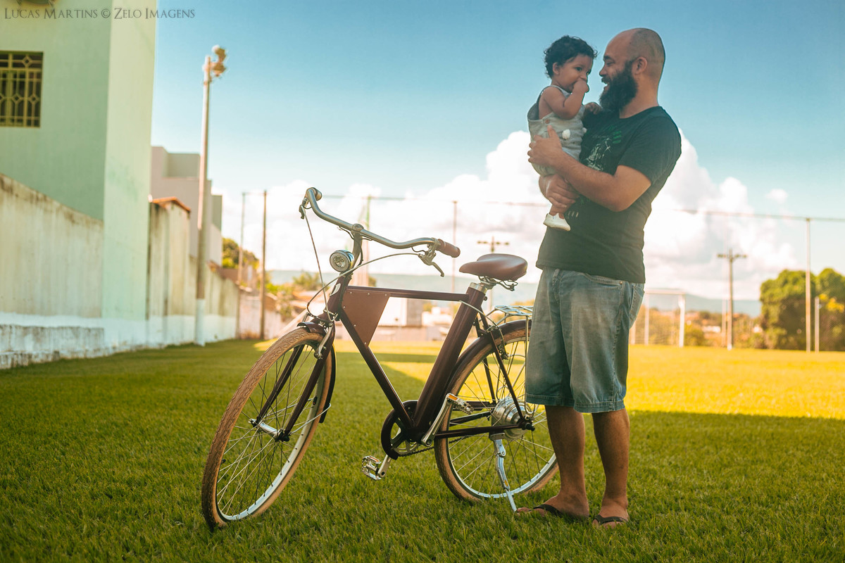 ensaio familia pai com filho no colo ao lado da bicicleta antiga