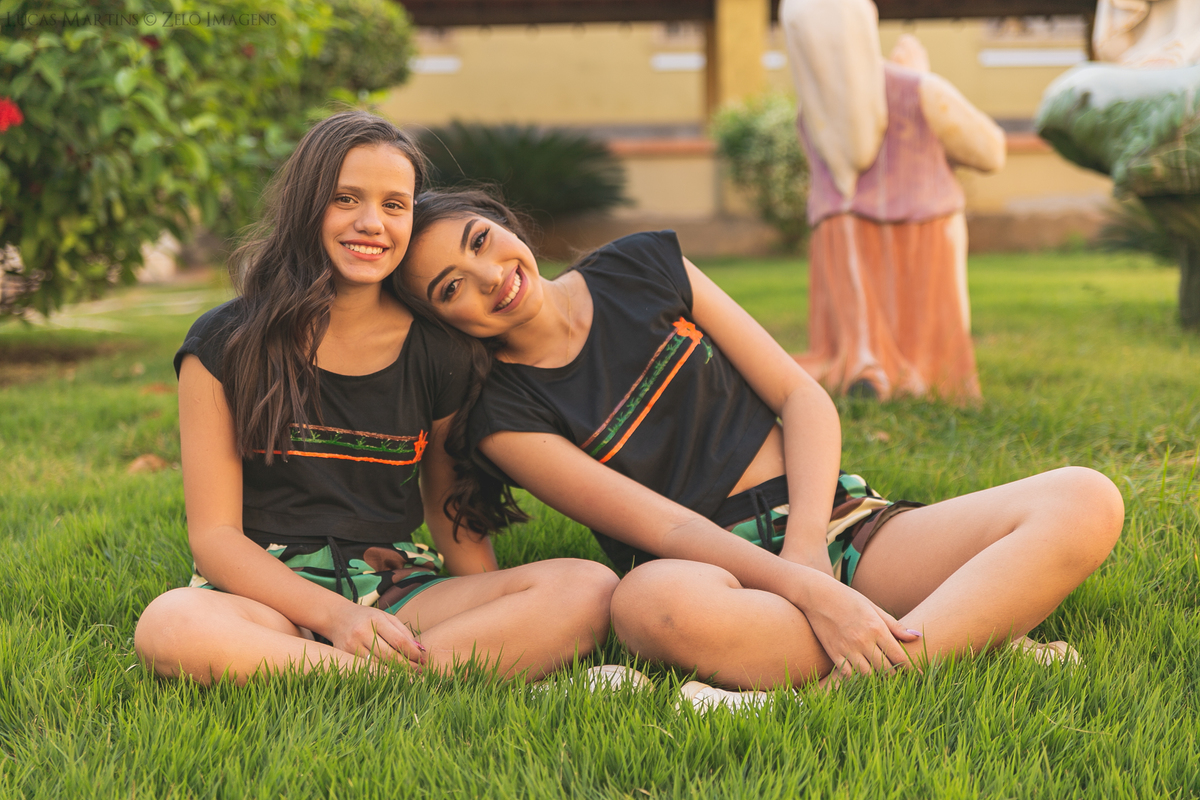 debutante junto com a prima na posando em uma grama verdinha