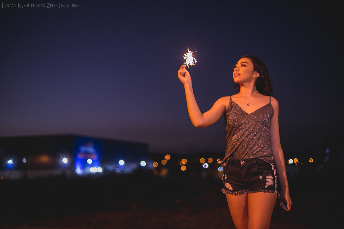 Debutante posando segurando um spark no final do dia