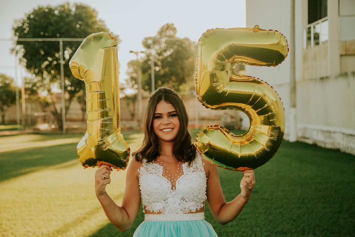 ensaio debutante segurando baloes com o numero 15