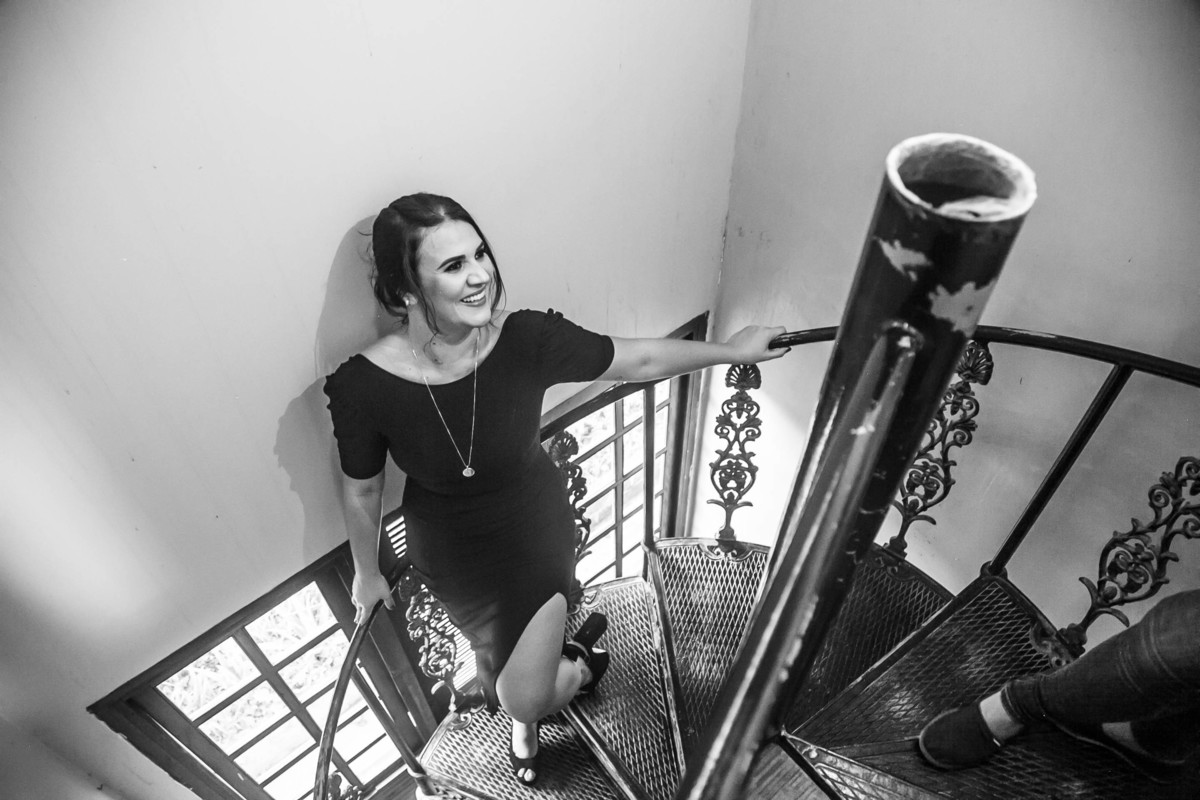 Foto em preto e branco de modelo usando vestido preto descendo escadas.
