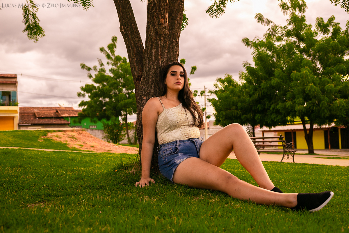 ensaio debutante sentada na grama encostada na árvore