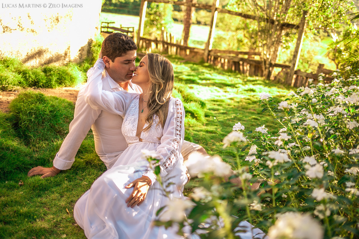 ensaio casal sentados na grama com flores brancas