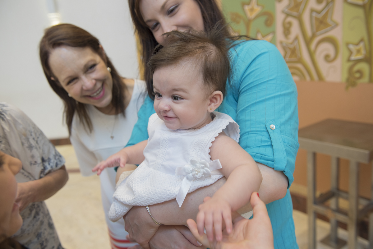 bebê recebendo carinho da família em batizado