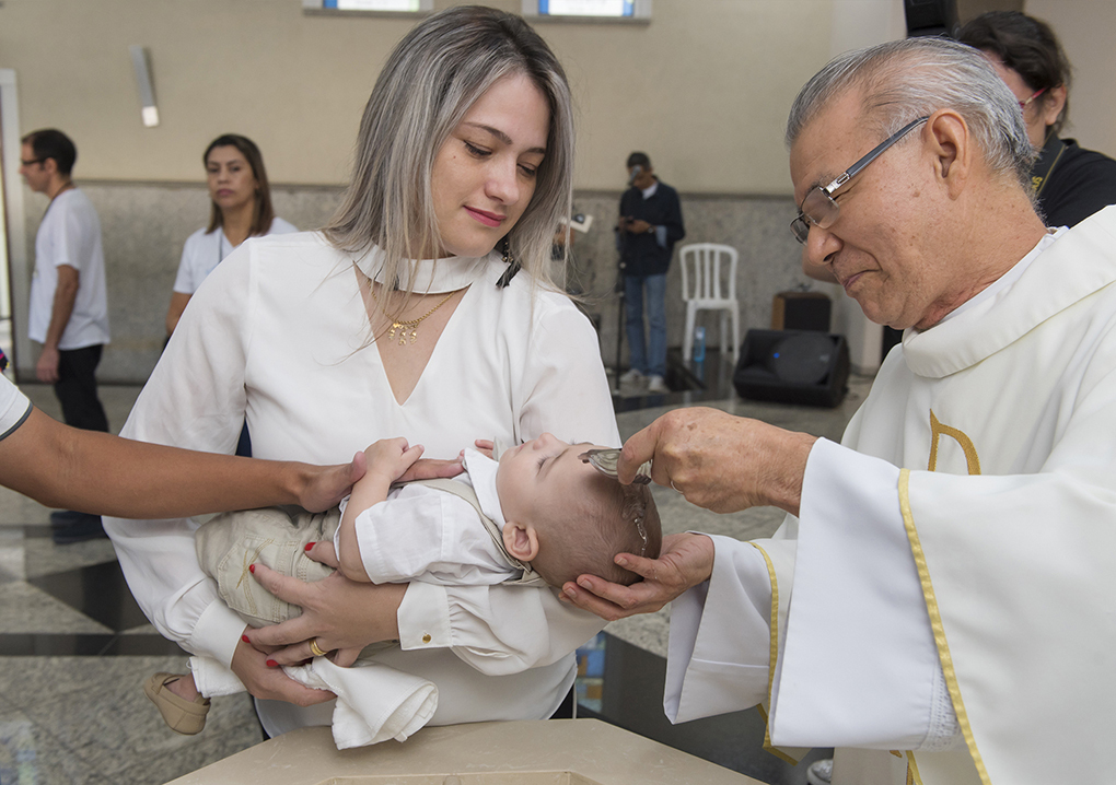 madrinha segura bebê no colo em momento da água na pis batismal