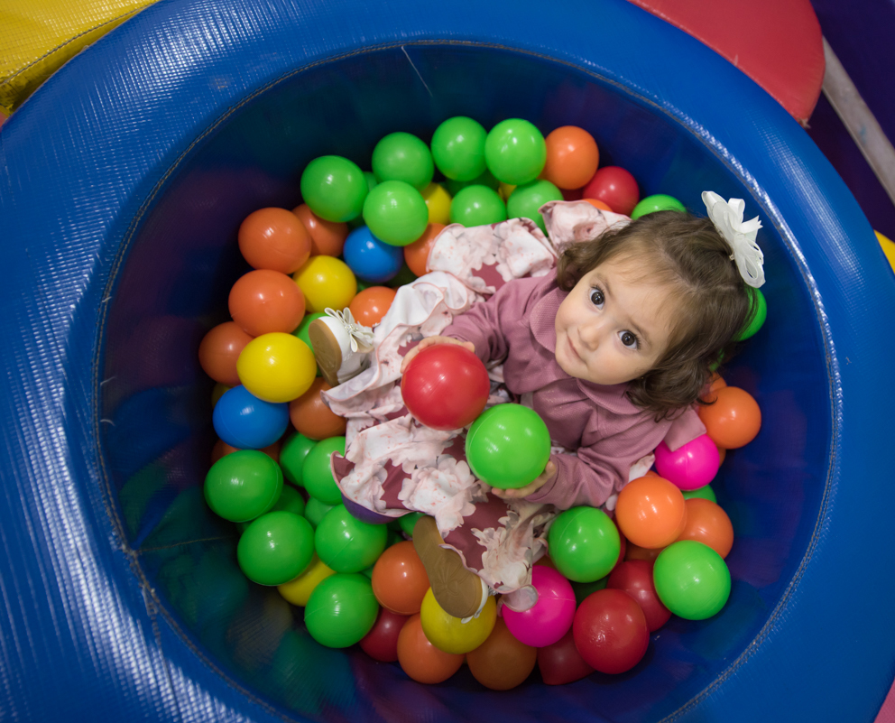 toda sorridente a menina na piscina de bolinhas olha para cima