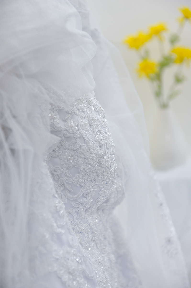 Detalhe do vestido da noiva enquanto ela se prepara para o grande dia