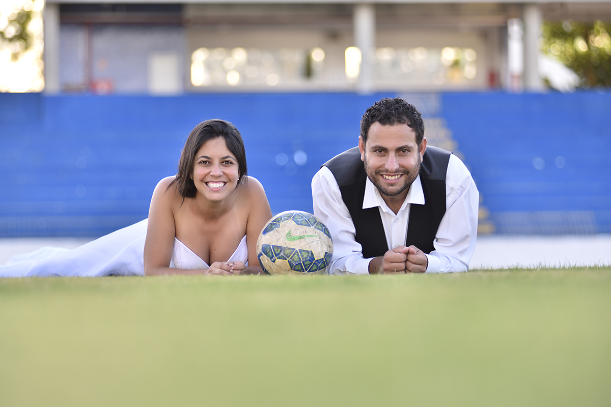 ensaio externo dos noivos deitados no campo com sorriso