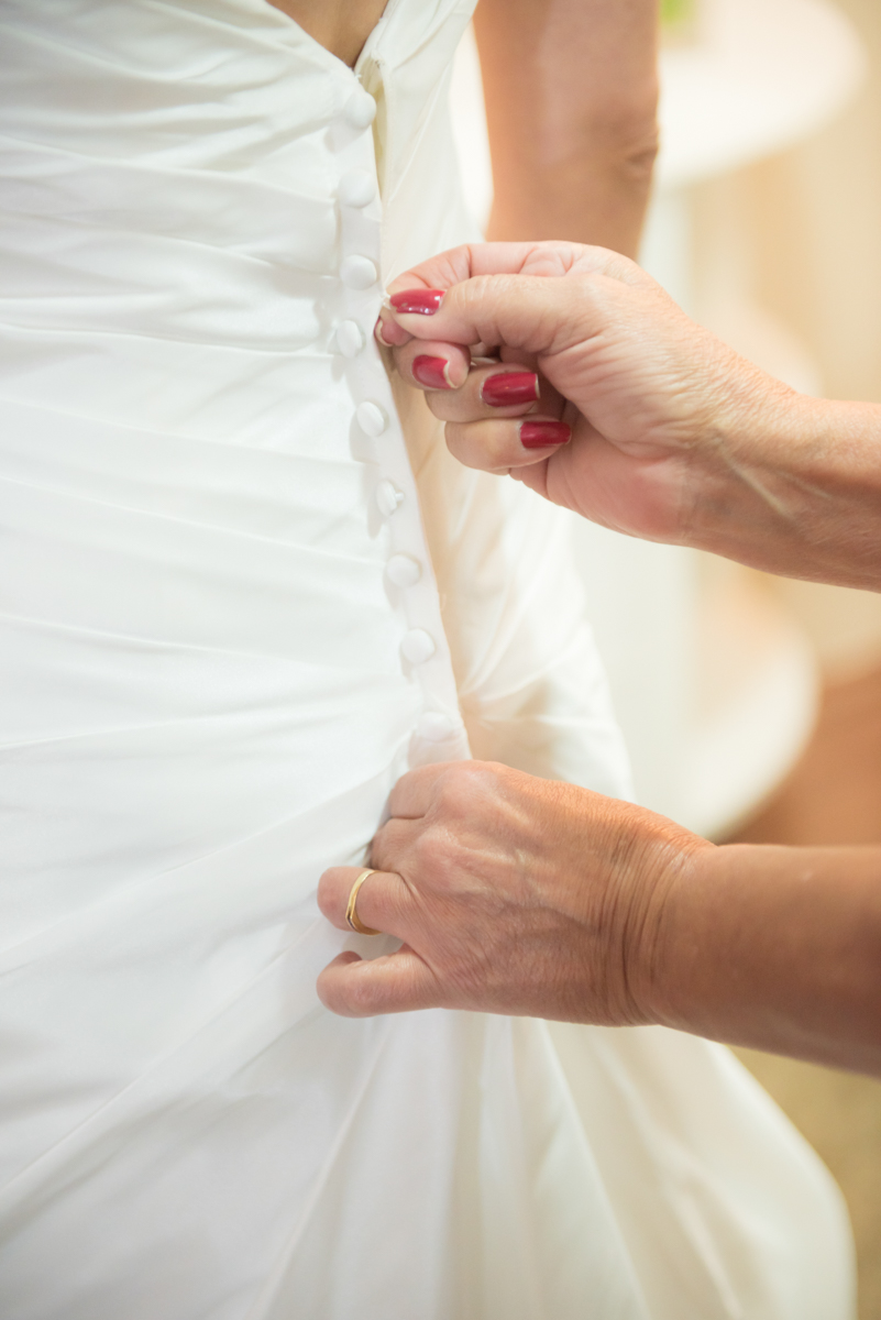 Fechando o vestido da noiva que tem muitos botões