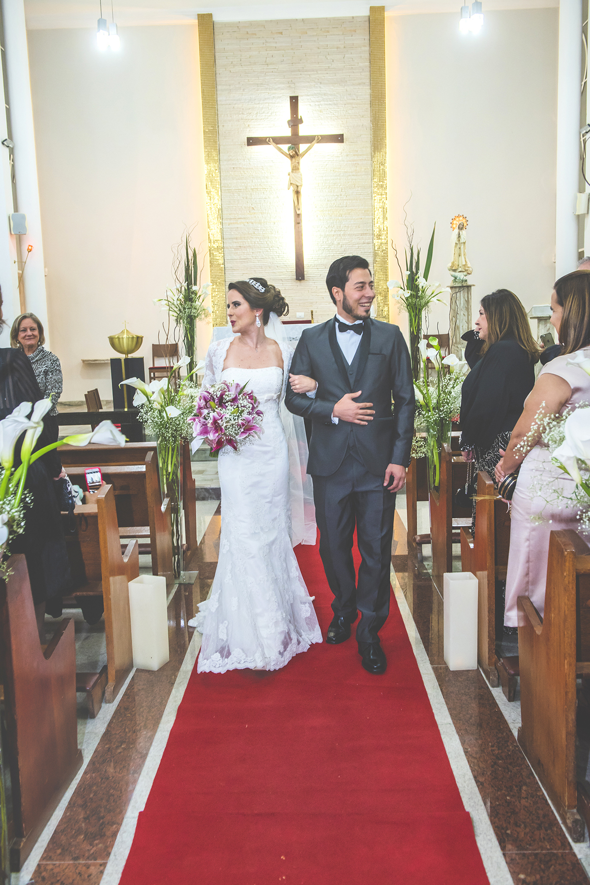 Noivos saindo da igreja e recebendo com sorriso os convidados