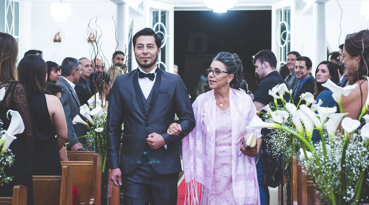 Foto em plano médio do noivo entrando com a mãe