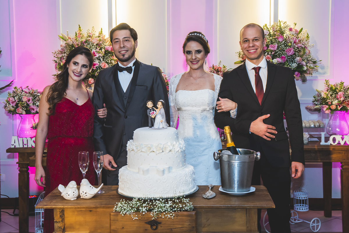 foto de casamento com os padrinhos ao lado do bolo