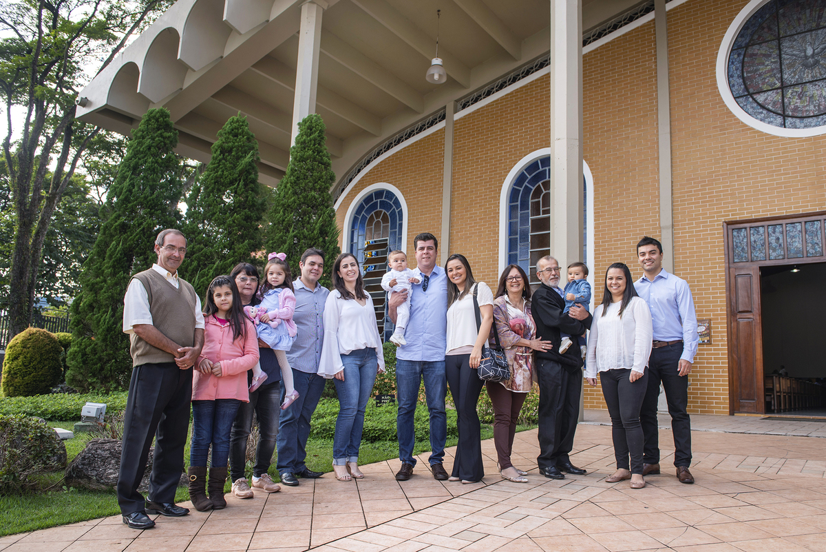 Família posa para foto de batizado em frente a Paróquia Sagrada Família 