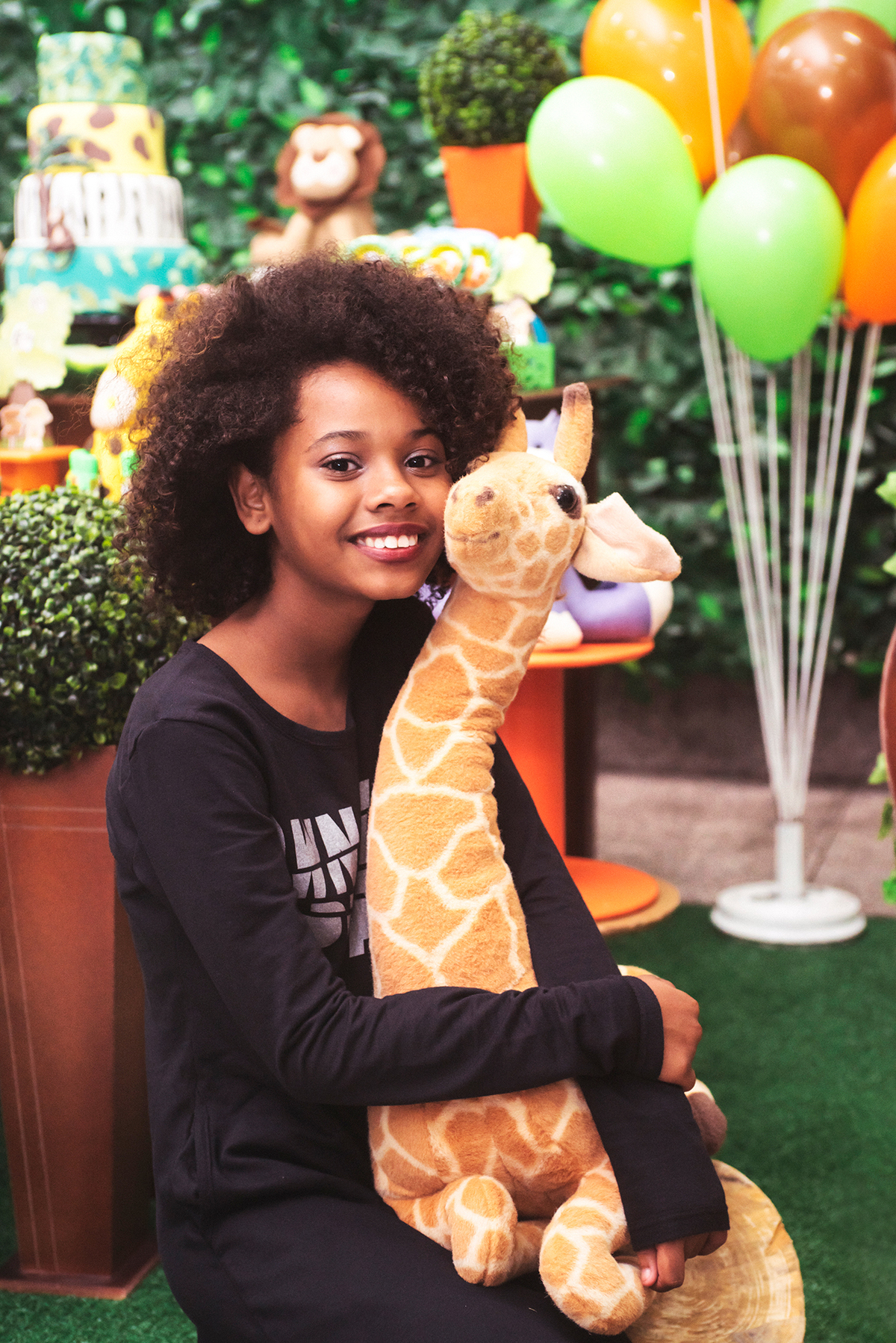 menina abraça a girafa em festa infantil e posa para foto