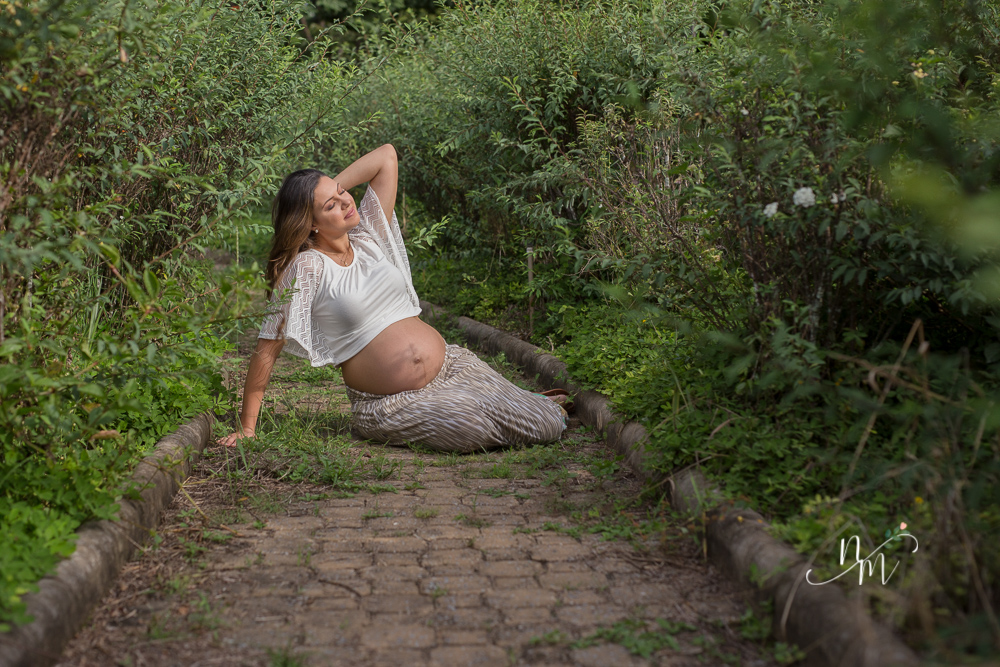 Foto tirada por Natália Melo Fotografia de uma gestante setada no chão em um parque em Belo Horizonte - MG
