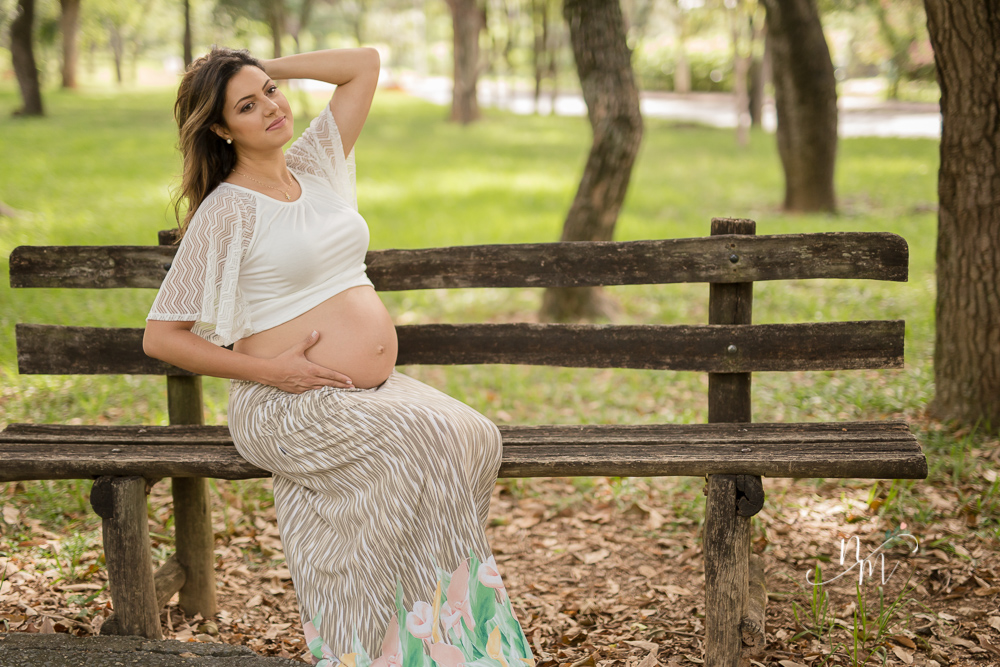 Foto tirada por Natália Melo Fotografia de uma gestante sentada num banco de um parque em Belo Horizonte - MG