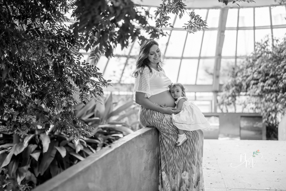 Foto tirada por Natália Melo Fotografia de uma gestante sentada com a filha no colo em um parque em Belo Horizonte - MG