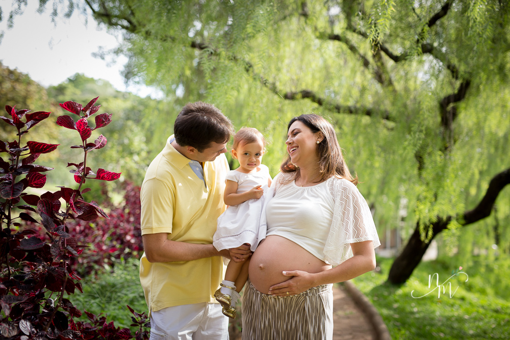 Foto tirada por Natália Melo Fotografia de uma gestante com a filha no colo em um parque em Belo Horizonte - MG