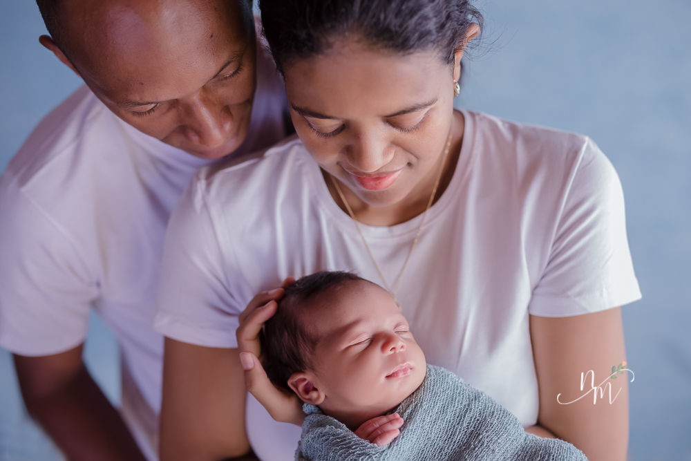 foto de bebe recem nascido enrolado num paninho azul no colo dos pais
