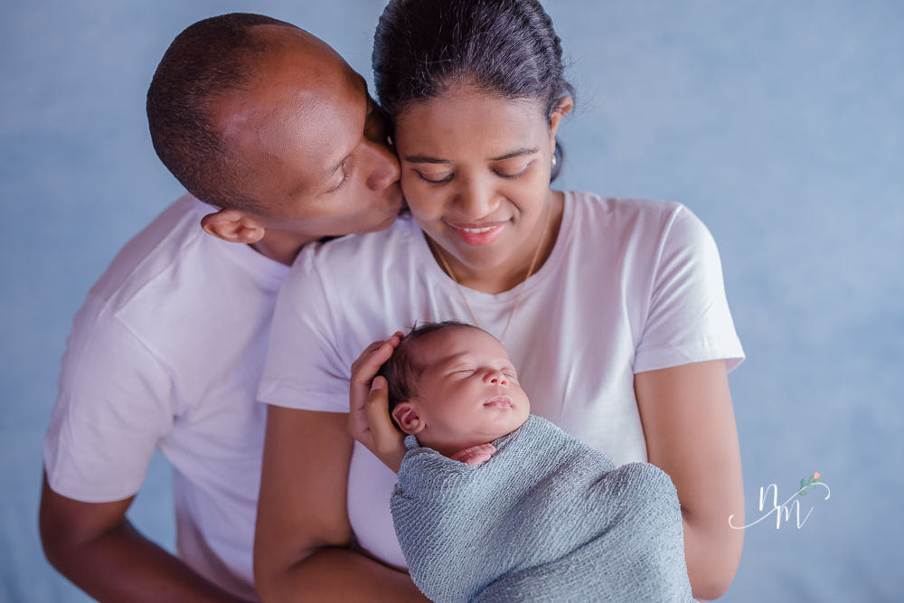foto de bebe recem nascido enrolado num paninho azul no colo dos pais