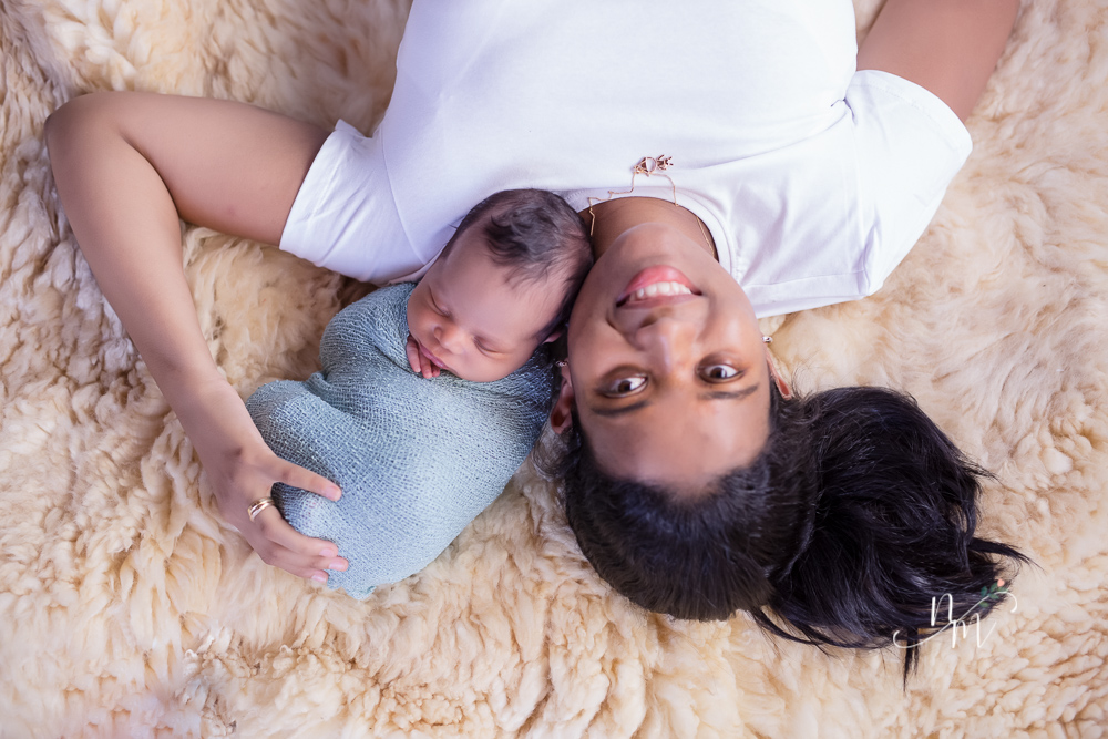 foto de bebe recem nascido enrolado num paninho azul no colo da mãe