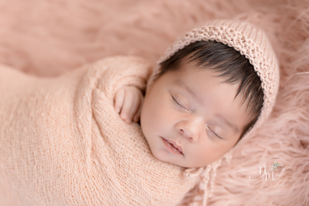 Bebê recém nascido enrolado no tecido rosa