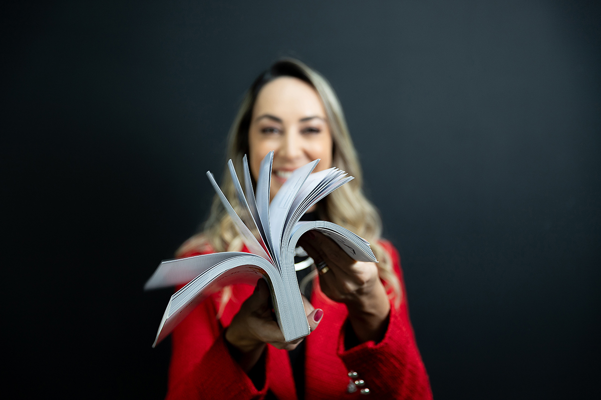 Biomédica segurando livro com as páginas abertas