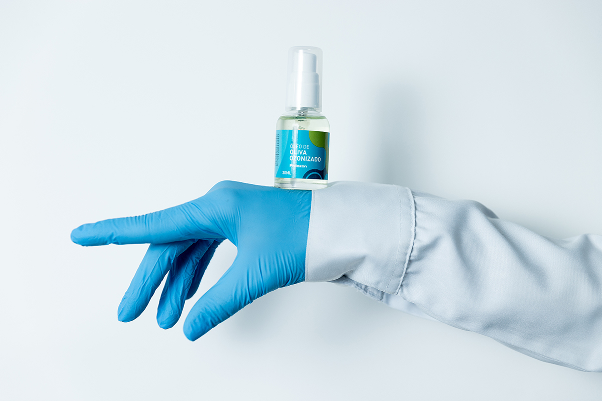 Mão de biomédica com luva azul com um frasco de ozônio