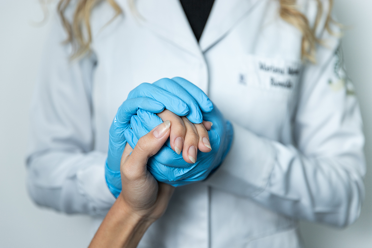 mão com luva azul abraçadas com mão de outra pessoa