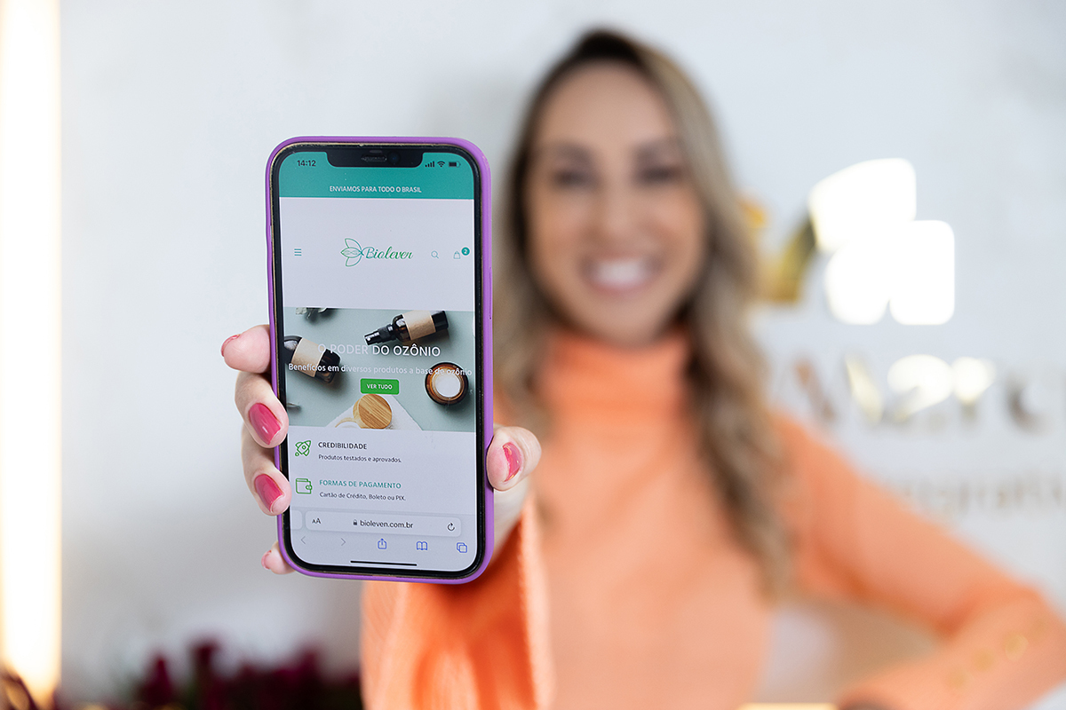 Biomédica segurando um celular com uma imagem do seu site