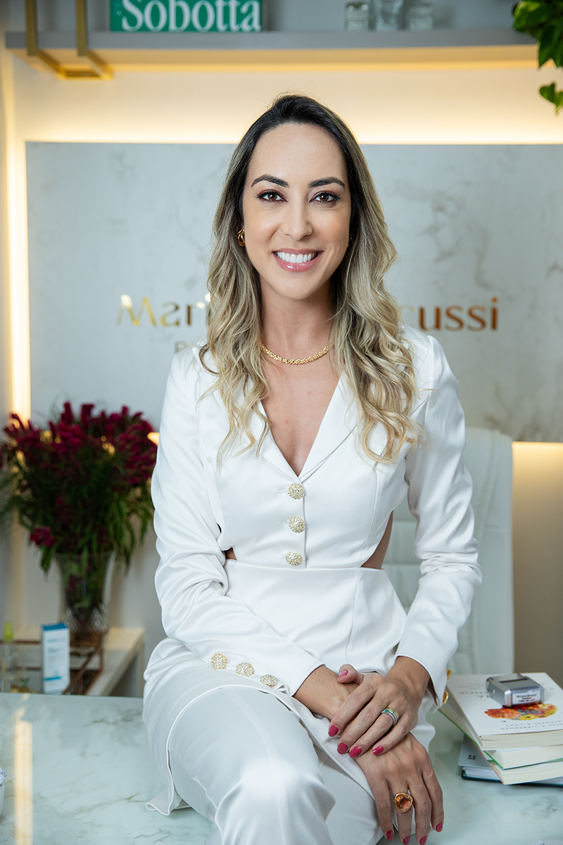 Biomédica sentada em cima de uma mesa