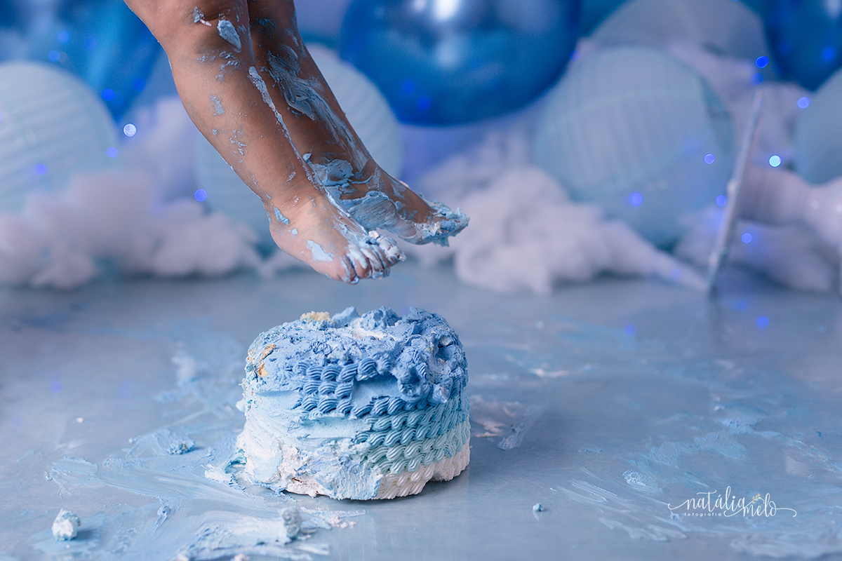 Menino enfiando o pé no bolo no Ensaio smash the cake no tema Balões feito no Estúdio Natália Melo Fotografia em Belo Horizonte - MG