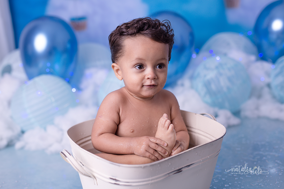 bebê tomando banho na tina, segurando o pé no Ensaio smash the cake no tema Balões feito no Estúdio Natália Melo Fotografia em Belo Horizonte - MG