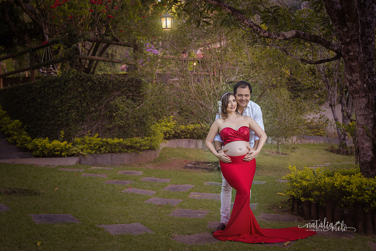 Gestante de vestido vermelha abraçada com esposo em Belo Horizonte - MG fotografada por Natália Melo Fotografia