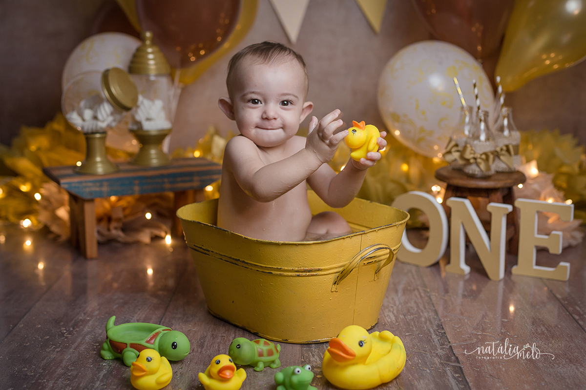 bebe dentro da tina amarela brincando com patinhos