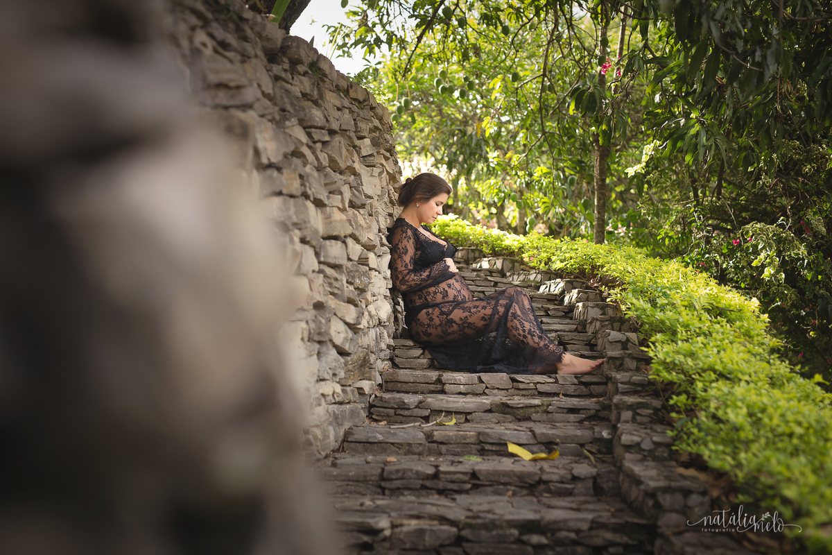 Gestante sentada numa escadaria de pedras com a mão na barriga em Belo Horizonte - MG