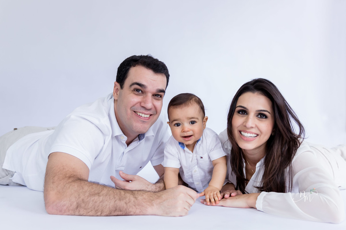 Ensaio de família feito por Natália Melo Fotografia, em Belo Horizonte -MG, onde pai, mãe e filho estão deitado de barriga para baixo no chão
