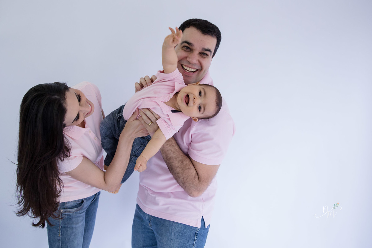 Ensaio de família feito por Natália Melo Fotografia, em Belo Horizonte -MG, onde pai e mãe carregam filho no colo com muita brincadeira e risadas