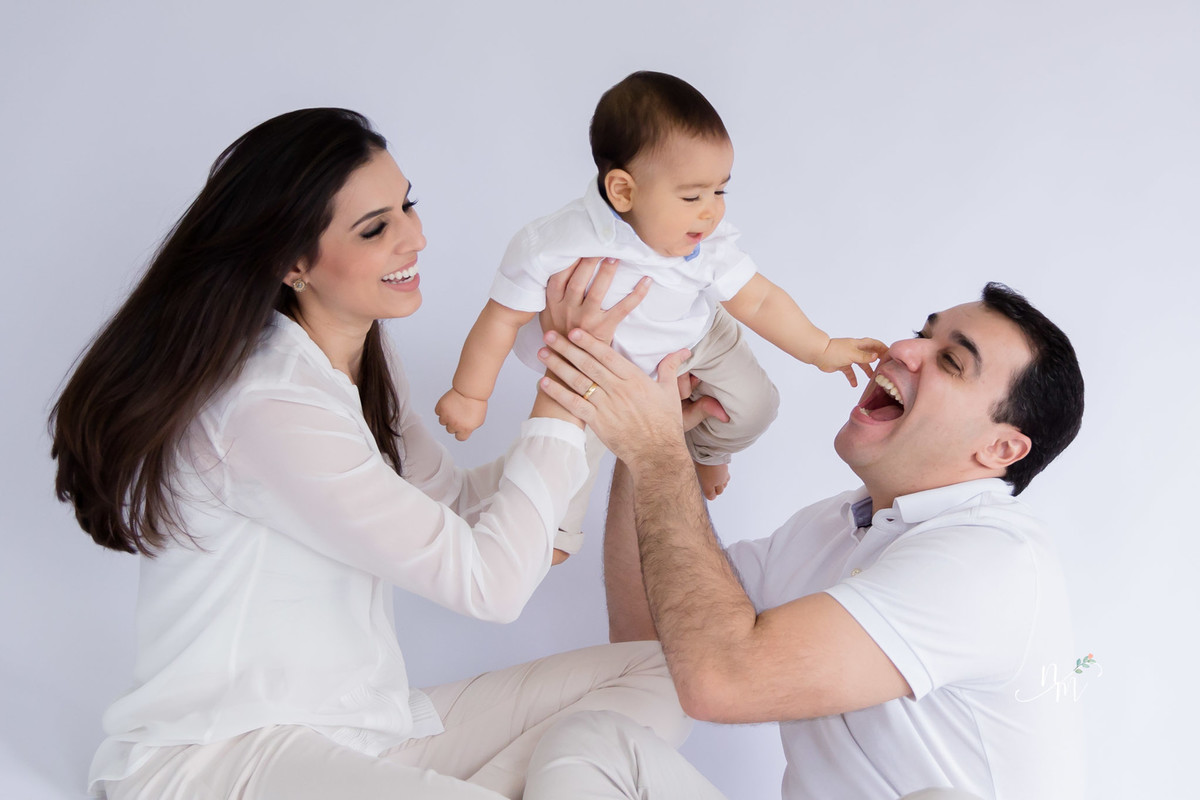 Ensaio de família feito por Natália Melo Fotografia, em Belo Horizonte -MG, onde pai e mãe carregam filho no colo e dão muitas risadas