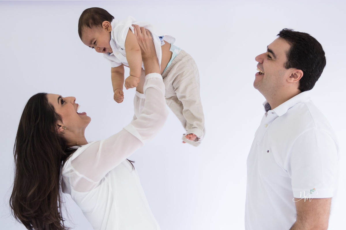 Ensaio de família feito por Natália Melo Fotografia, em Belo Horizonte -MG, onde a mãe carrega filho e joga ligeiramente para o alto e pai sorri