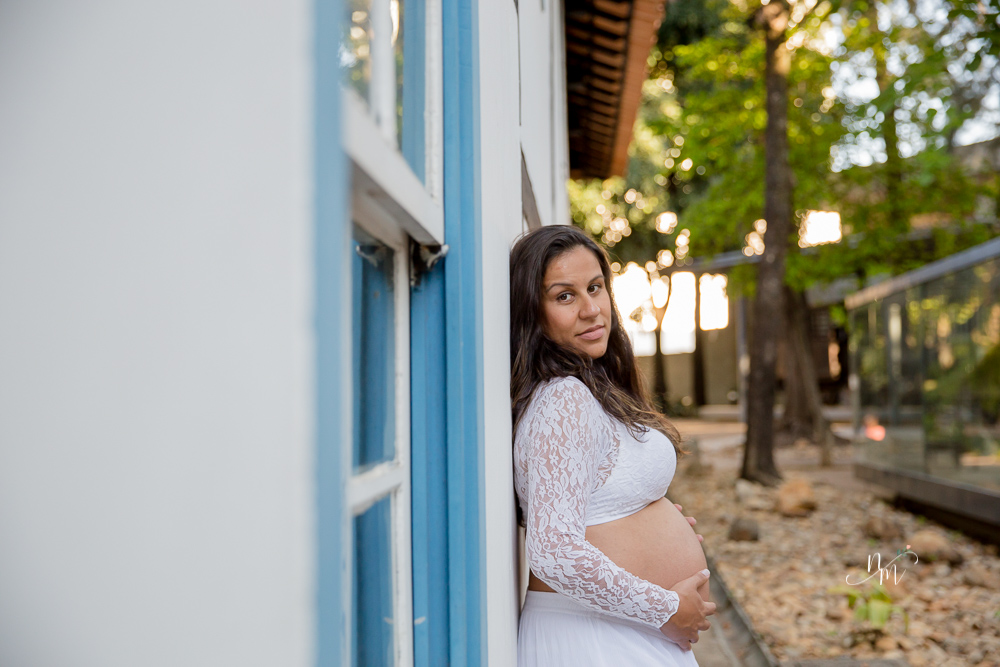 ensaio de gestante feito por Natália Melo Fotografia em Belo Horizonte -MG, no Museu Histórico Abílio Barreto, onde a Flaviana está encostada na parede olhando para a barriga