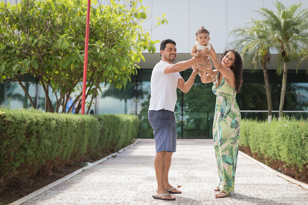 Ensaio de Família feito por Natália Melo Fotografia no Clube Jaraguá em Belo Horizonte - MG, onde pai e mãe carregam Lara e brincam com ela no colo