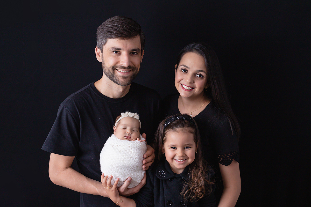 Recem nascida enrolada no tecido com a irmã e os pais no Estudio Natalia Melo Fotografia em Belo Horizonte - MG