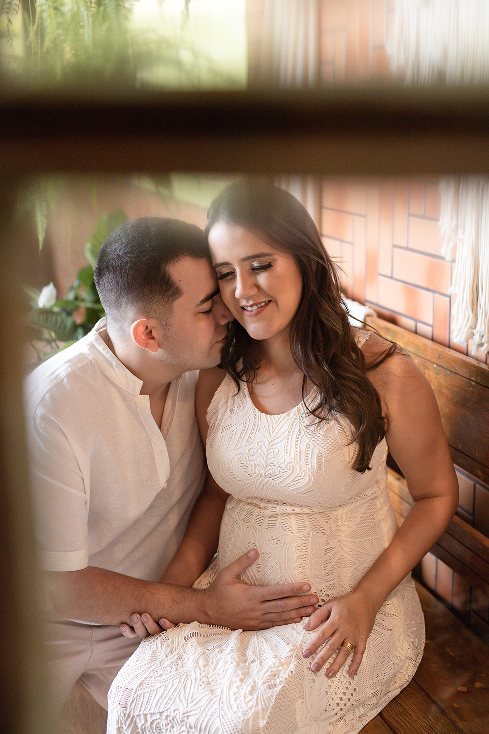 Gestante e esposo com roupa branca 
 sentado abraçados de olhos fechados em Belo Horizonte - MG