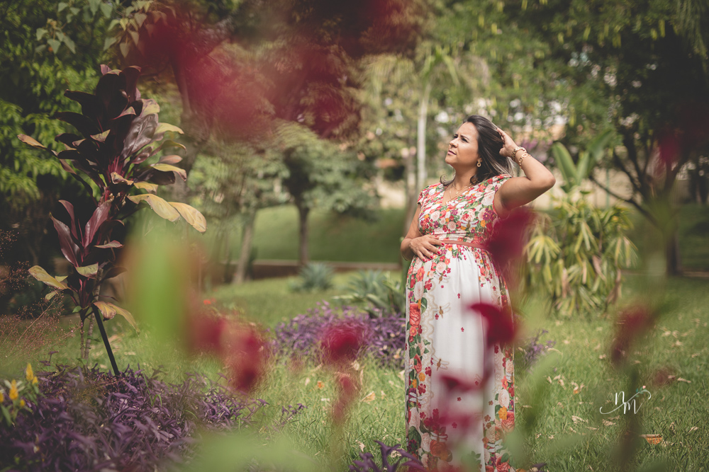 Gestante olhando para a barriga em uma área verde em Belo Horizonte  - MG fotografada por Natália Melo